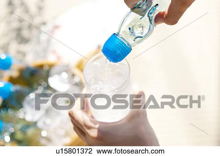 Stock Image - Woman pouring soda in glass. Fotosearch