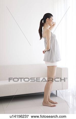 Stock Photo - Woman standing by a window. Fotosearch