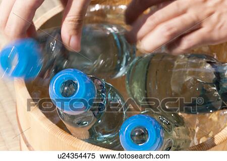Stock Photography - Woman taking out a bottle of soda from a bucket. Fotosearch