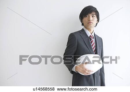 Stock Photo - Young businessman holding a helmet. Fotosearch