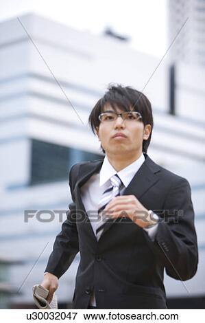 Stock Photo - Young businessman holding newspaper and running. Fotosearch