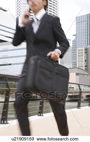 Young businessman on cell phone running View Large Photo Image Stock Photo - Young businessman on cell phone running. Fotosearch