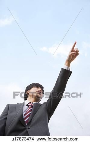Picture - Young businessman pointing, low angle view. Fotosearch