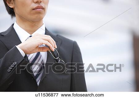 Young businessman putting away his glasses into his pocket View Large Photo Image Stock Photo - Young businessman putting away his glasses into his pocket. Fotosearch