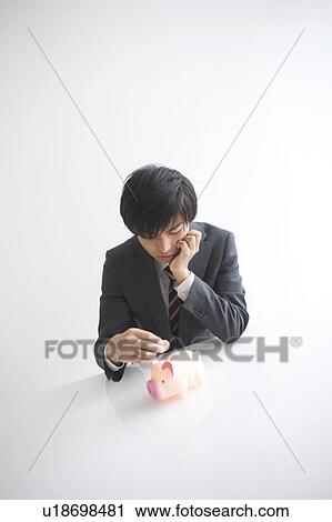 Young businessman putting coin into piggy bank View Large Photo Image Stock Image - Young businessman putting coin into piggy bank. Fotosearch