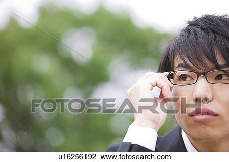 Young businessman touching his glasses View Large Photo Image Stock Image - Young businessman touching his glasses. Fotosearch
