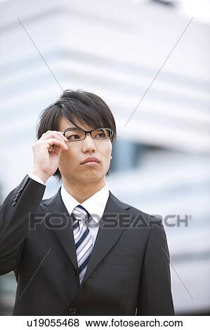 Young businessman touching his glasses View Large Photo Image Stock Photo - Young businessman touching his glasses. Fotosearch