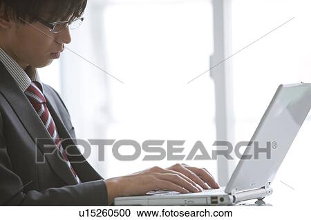 Stock Image - Young businessman using laptop. Fotosearch