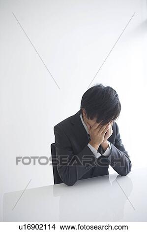 Picture - Young businessman with head in hands. Fotosearch