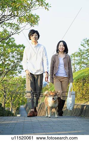Stock Image - Young Couple Walking a Dog. Fotosearch