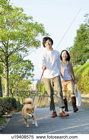 Stock Photography - Young Couple Walking a Dog. Fotosearch
