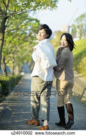 Stock Image - Young Couple Walking and Looking Back at Camera. Fotosearch