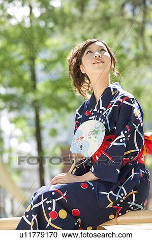 Stock Image - Young woman wearing Yukata and looking up. Fotosearch