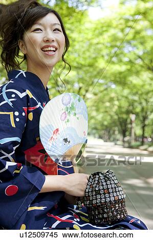 Stock Photography - Young woman wearing Yukata sitting on bench. Fotosearch