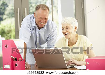 Stock Image - Adult Son And Senior Mother Using Laptop At Home. Fotosearch