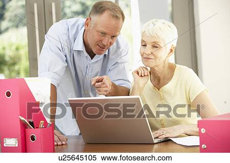 Stock Photography - Adult Son And Senior Mother Using Laptop At Home. Fotosearch