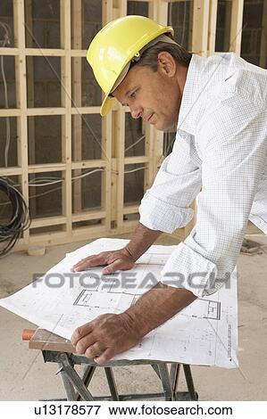 Architect Studying Plans In New Home View Large Photo Image Stock Photo - Architect Studying Plans In New Home. Fotosearch