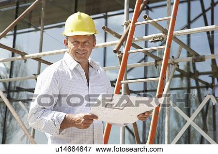 Architect Studying Plans Outside New Home View Large Photo Image Stock Photo - Architect Studying Plans Outside New Home. Fotosearch