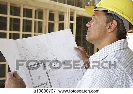 Stock Photo - Architect With Plans In New Home. Fotosearch