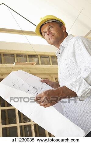 Stock Photography - Architect With Plans In New Home. Fotosearch