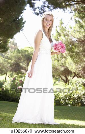 Stock Image - Bride Wearing Dress Holding Bouqet At Wedding. Fotosearch