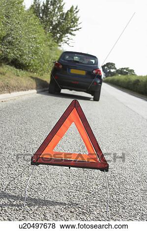 Stock Photo - Car Broken Down On Country Road With Hazard Warning Sign In Foreground. Fotosearch