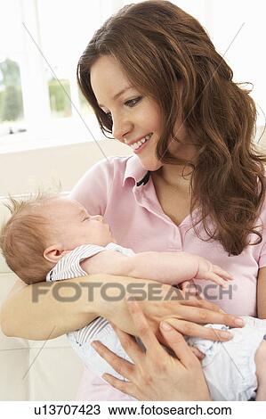 Stock Image - Close Up Of Affectionate Mother Cuddling Baby Boy At Home. Fotosearch