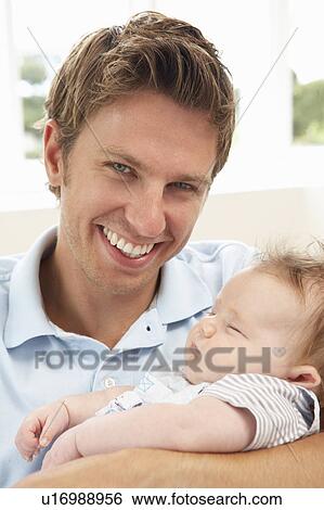 Stock Photograph - Close Up Of Father Cuddling Newborn Baby Boy At Home. Fotosearch