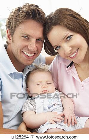 Stock Photo - Close Up Of Parents Cuddling Newborn Baby Boy At Home. Fotosearch