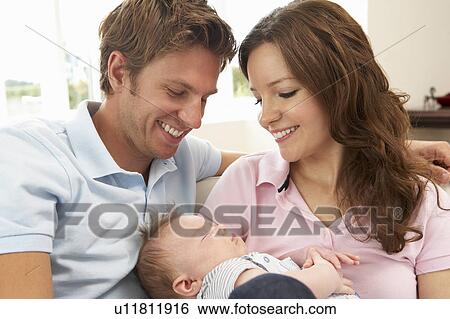 Stock Photograph - Close Up Of Parents Cuddling Newborn Baby Boy At Home. Fotosearch