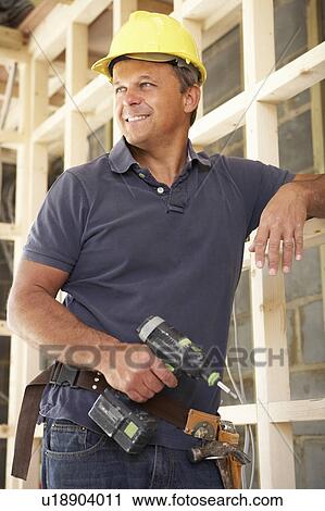 Stock Image - Construction Worker Building Timber Frame In New Home. Fotosearch