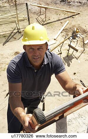 Stock Photograph - Construction Worker Climbing Ladder On Building Site For New Home. Fotosearch