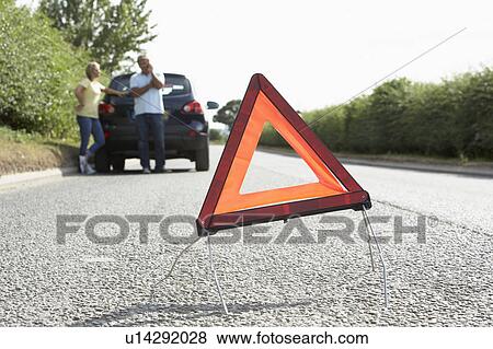Couple Broken Down On Country Road With Hazard Warning Sign In Foreground View Large Photo Image Stock Photo - Couple Broken Down On Country Road With Hazard Warning Sign In Foreground. Fotosearch