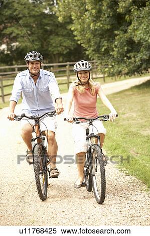 Couple Cycling In Countryside Wearing Safety Helmets View Large Photo Image Stock Photography - Couple Cycling In Countryside Wearing Safety Helmets. Fotosearch
