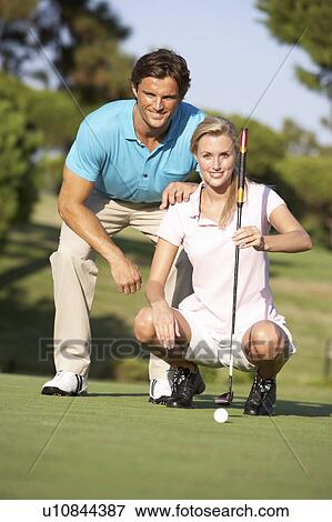 Couple Golfing On Golf Course Lining Up Putt On Green View Large Photo Image Stock Photo - Couple Golfing On Golf Course Lining Up Putt On Green. Fotosearch