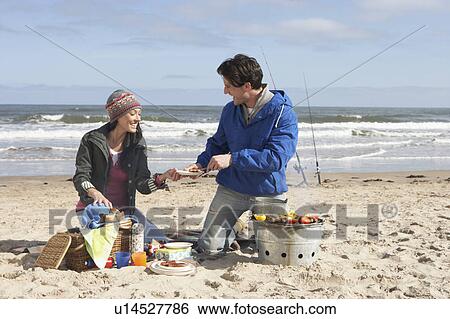Stock Photograph - Couple Having Barbeque On Winter Beach. Fotosearch