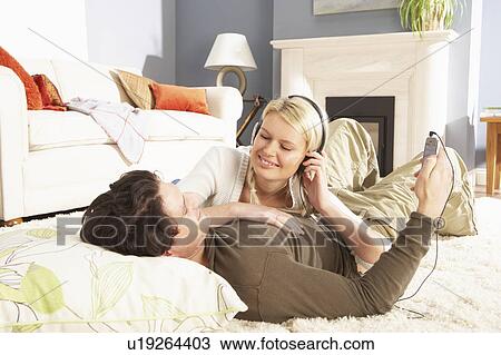 Couple Listening To MP3 Player On Headphones Relaxing Laying On Rug At Home View Large Photo Image Stock Image - Couple Listening To MP3 Player On Headphones Relaxing Laying On Rug At Home . Fotosearch