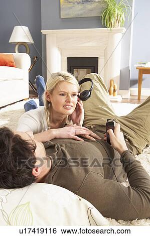 Couple Listening To MP3 Player On Headphones Relaxing Laying On Rug At Home View Large Photo Image Stock Photograph - Couple Listening To MP3 Player On Headphones Relaxing Laying On Rug At Home . Fotosearch