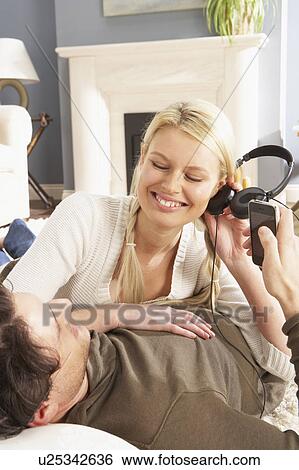 Couple Listening To MP3 Player On Headphones Relaxing Laying On Rug At Home View Large Photo Image Stock Photograph - Couple Listening To MP3 Player On Headphones Relaxing Laying On Rug At Home . Fotosearch