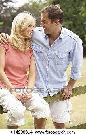 Couple Relaxing In Countryside Sitting On Fence View Large Photo Image Picture - Couple Relaxing In Countryside Sitting On Fence. Fotosearch