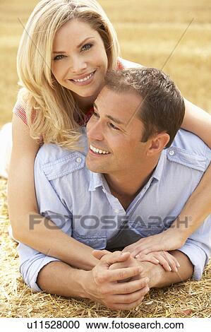 Stock Image - Couple Relaxing In Summer Harvested Field. Fotosearch