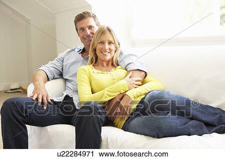 Stock Image - Couple Relaxing On Sofa At Home. Fotosearch