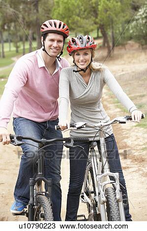 Stock Image - Couple riding bicycle in park. Fotosearch