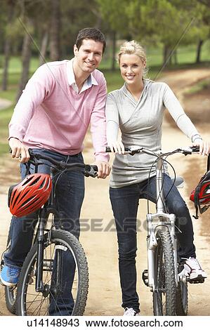 Stock Image - Couple riding bicycle in park. Fotosearch