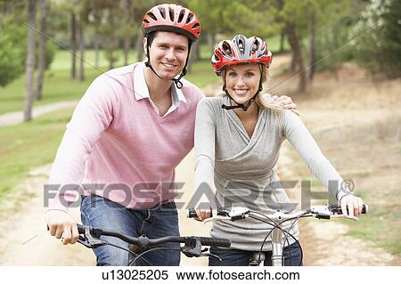 Couple riding bicycle in park View Large Photo Image Stock Photography - Couple riding bicycle in park. Fotosearch
