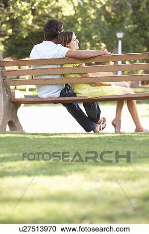 Stock Image - Couple Sitting Together On Park Bench. Fotosearch