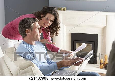 Couple Using Laptop And Discussing Household Bills Sitting On Sofa At Home View Large Photo Image Stock Photo - Couple Using Laptop And Discussing Household Bills Sitting On Sofa At Home. Fotosearch