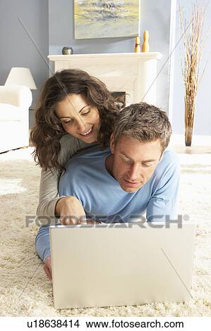 Couple Using Laptop Relaxing Laying On Rug At Home View Large Photo Image Picture - Couple Using Laptop Relaxing Laying On Rug At Home. Fotosearch