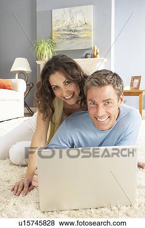 Couple Using Laptop Relaxing Laying On Rug At Home View Large Photo Image Stock Photo - Couple Using Laptop Relaxing Laying On Rug At Home. Fotosearch