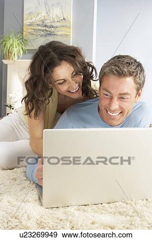 Couple Using Laptop Relaxing Laying On Rug At Home View Large Photo Image Stock Photo - Couple Using Laptop Relaxing Laying On Rug At Home. Fotosearch